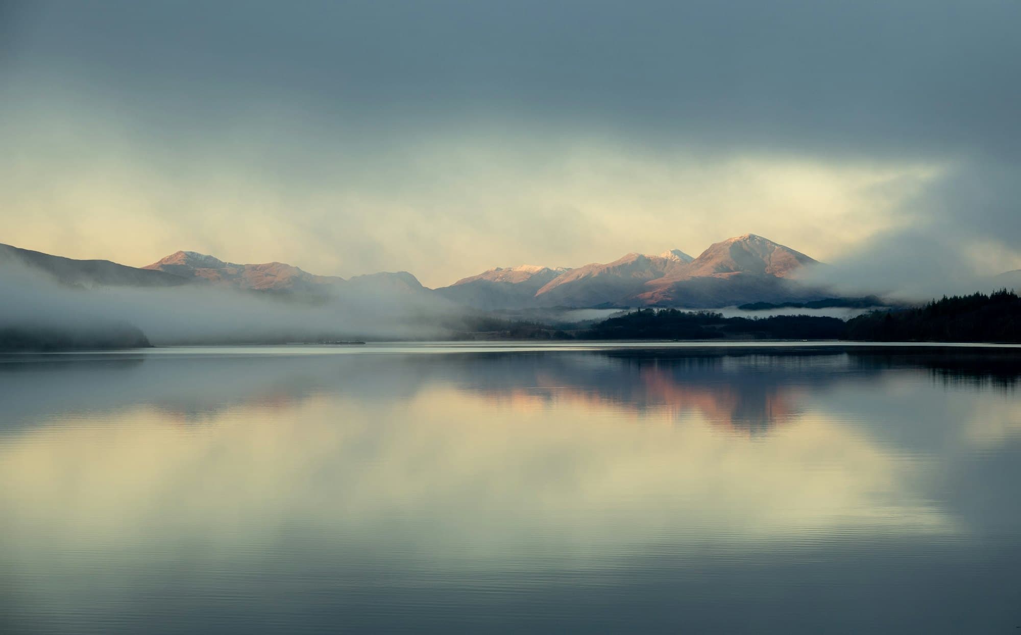 A still lake under low mist, the far shore just visible.