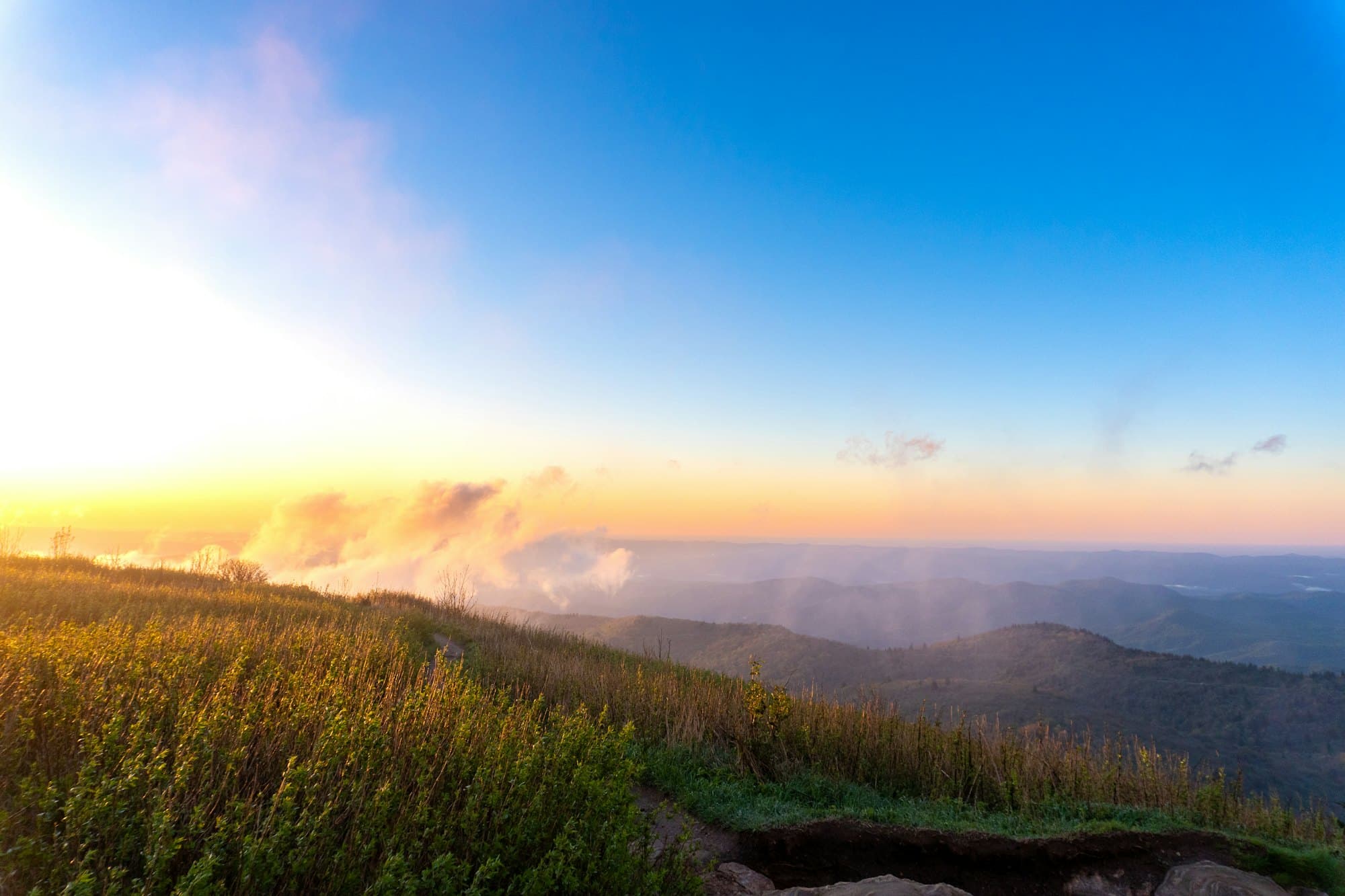 Sunrise breaking over a long mountain ridge, cloud filling the valley below.
