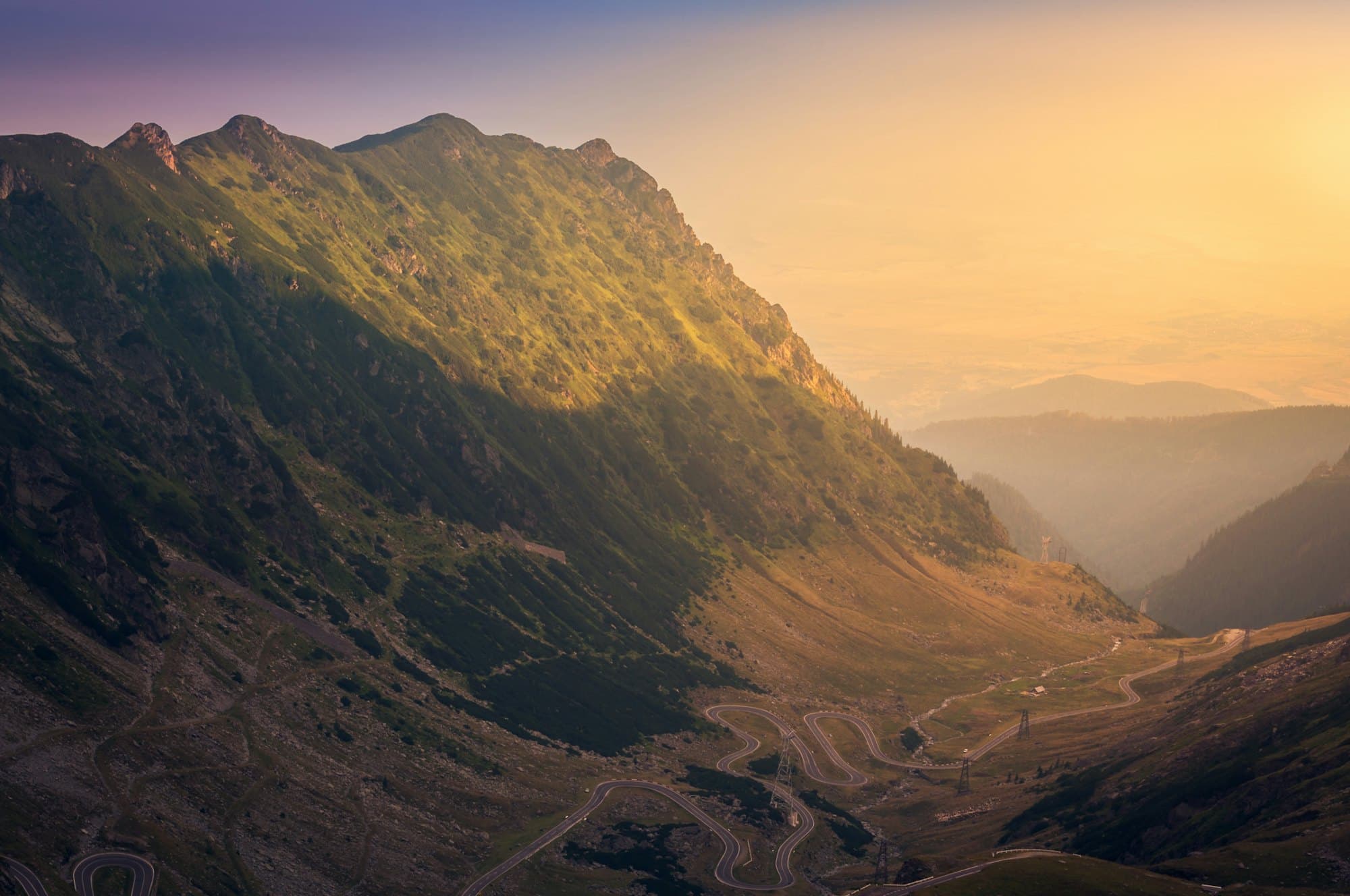 Late light running down a wide valley, ridges receding into haze.